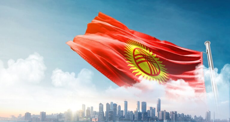 Kyrgyzstan,National,Flag,Waving,In,The,Sky,With,Cityscape.,Kyrgyzstan